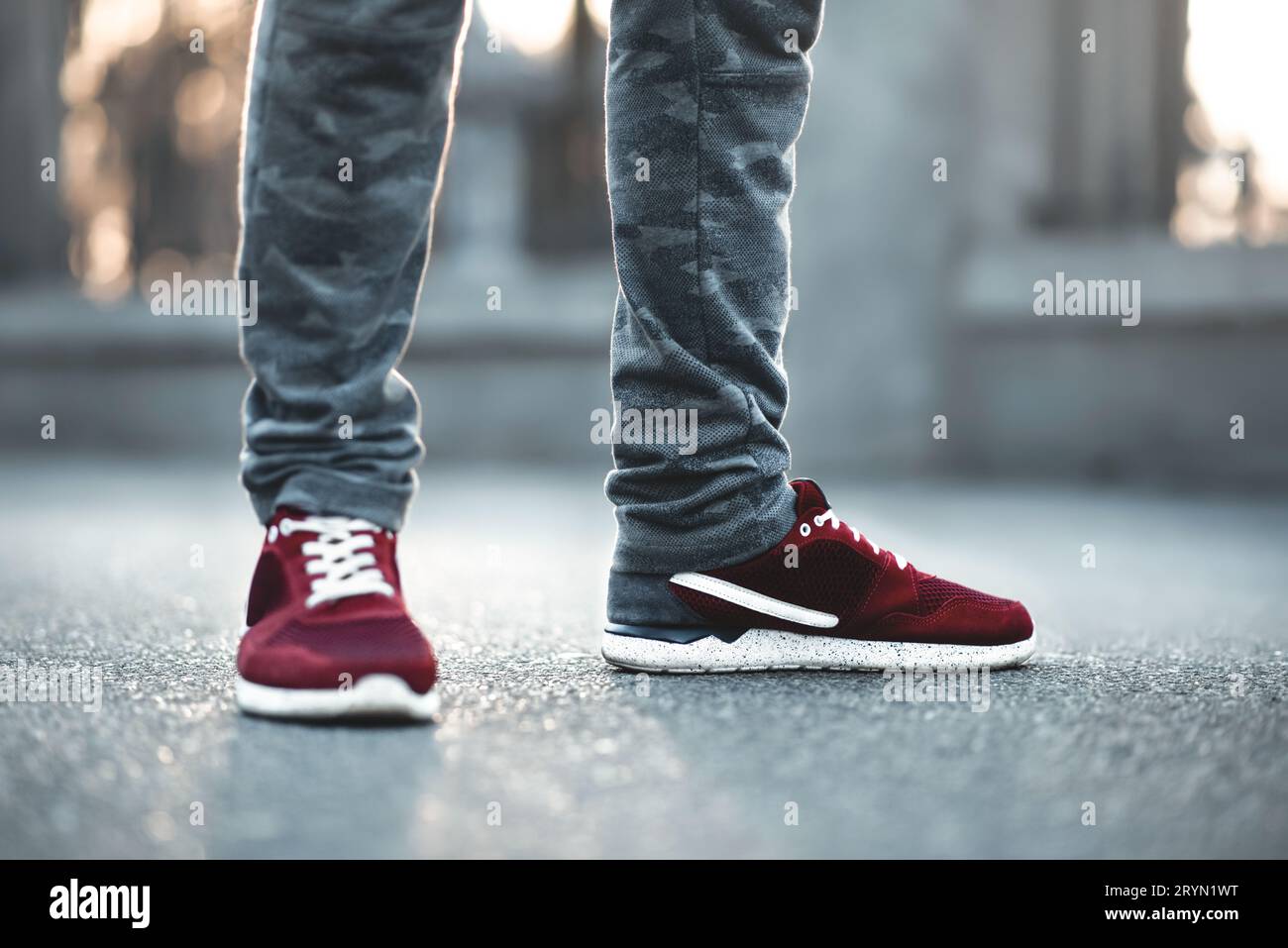 Rosso sport sneakers close-up su asfalto. Gambe e scarpe dal Angolo inferiore Foto Stock
