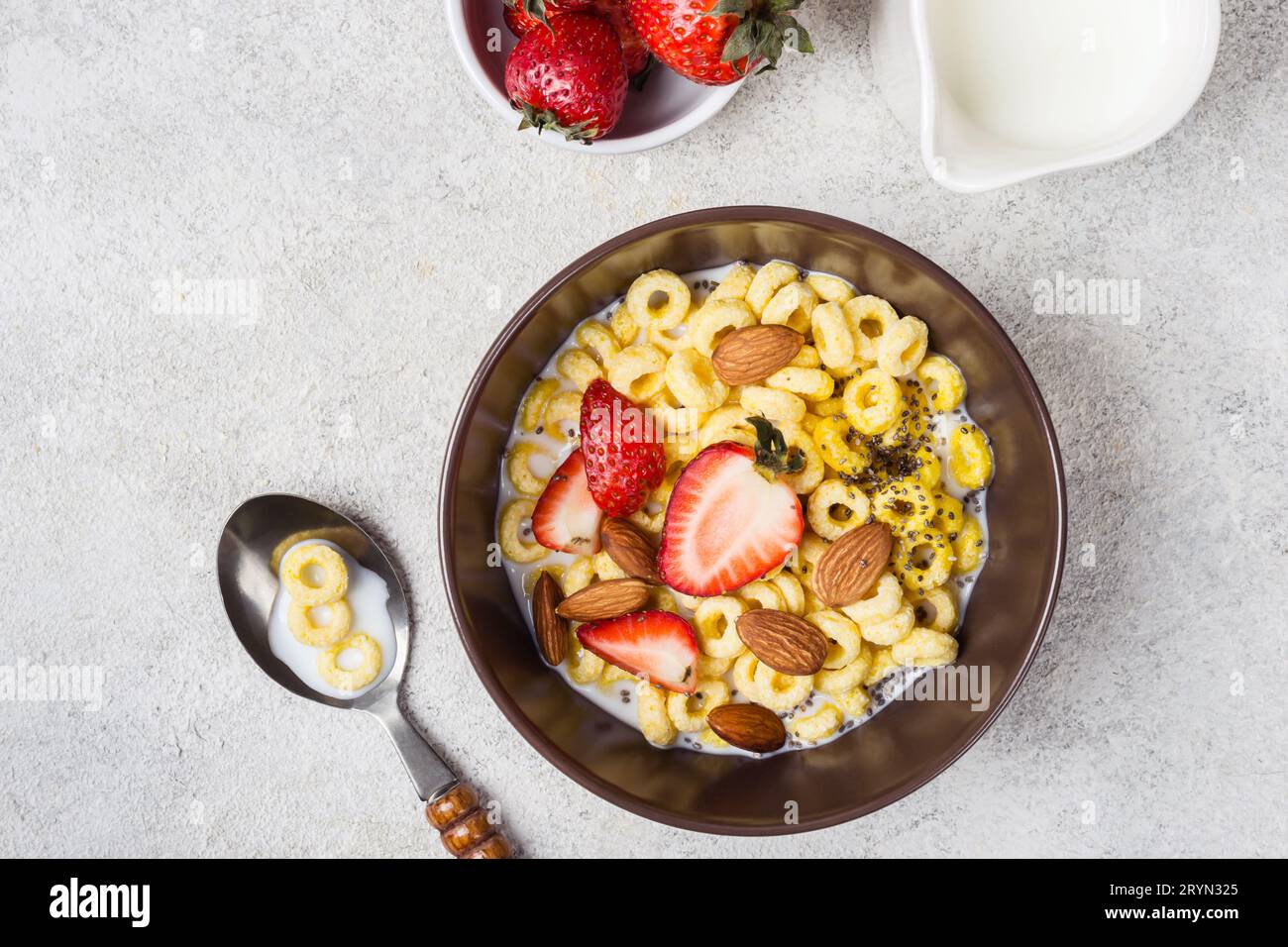 Recipiente con anelli di cereali cheerios, fragole e latte. Colazione tradizionale Foto Stock