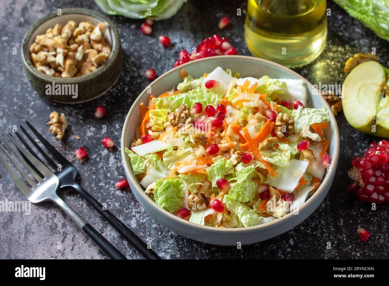 Insalata di cavolo cinese con dieta autunnale verdure fresche, carote, mela, noci e melograno con condimento in vinaigrette su una S scura Foto Stock