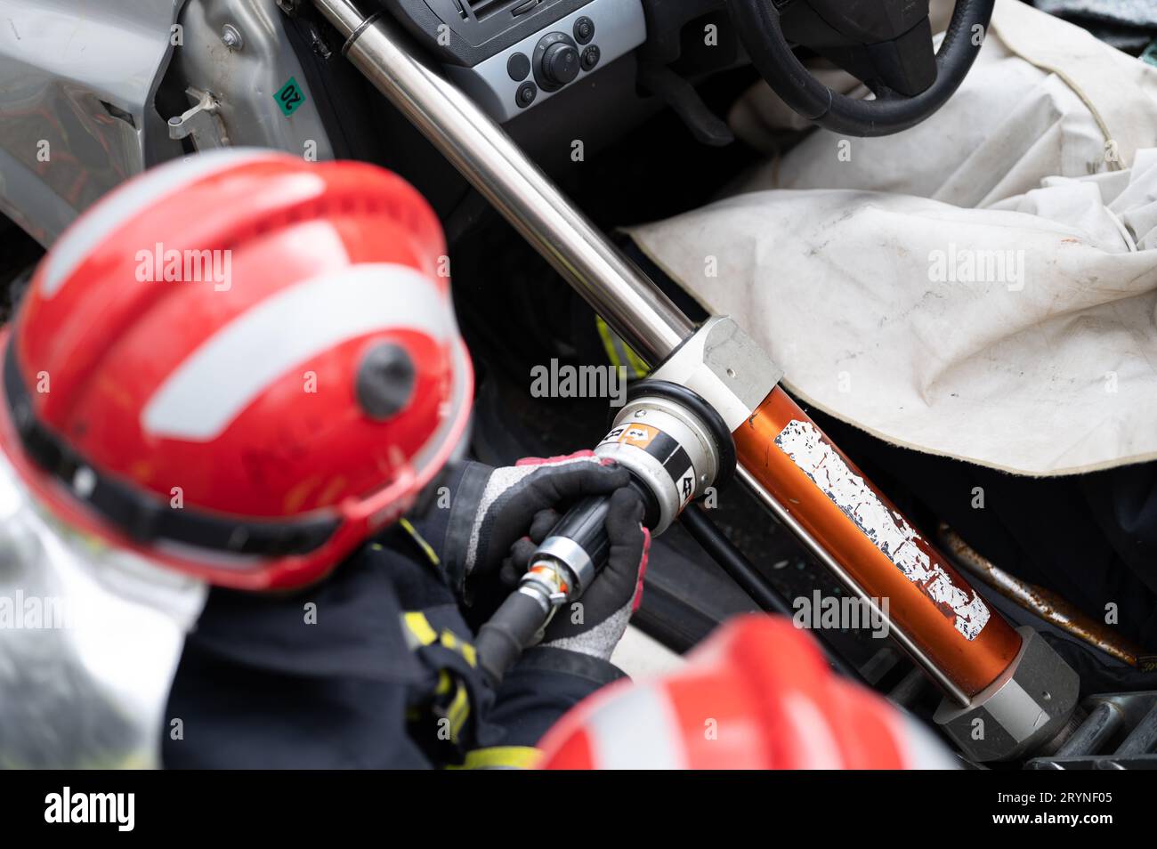 Vigili del fuoco che utilizzano attrezzi idraulici durante un addestramento alle operazioni di soccorso. I soccorritori sbloccano il passeggero in auto dopo un incidente. Foto Stock