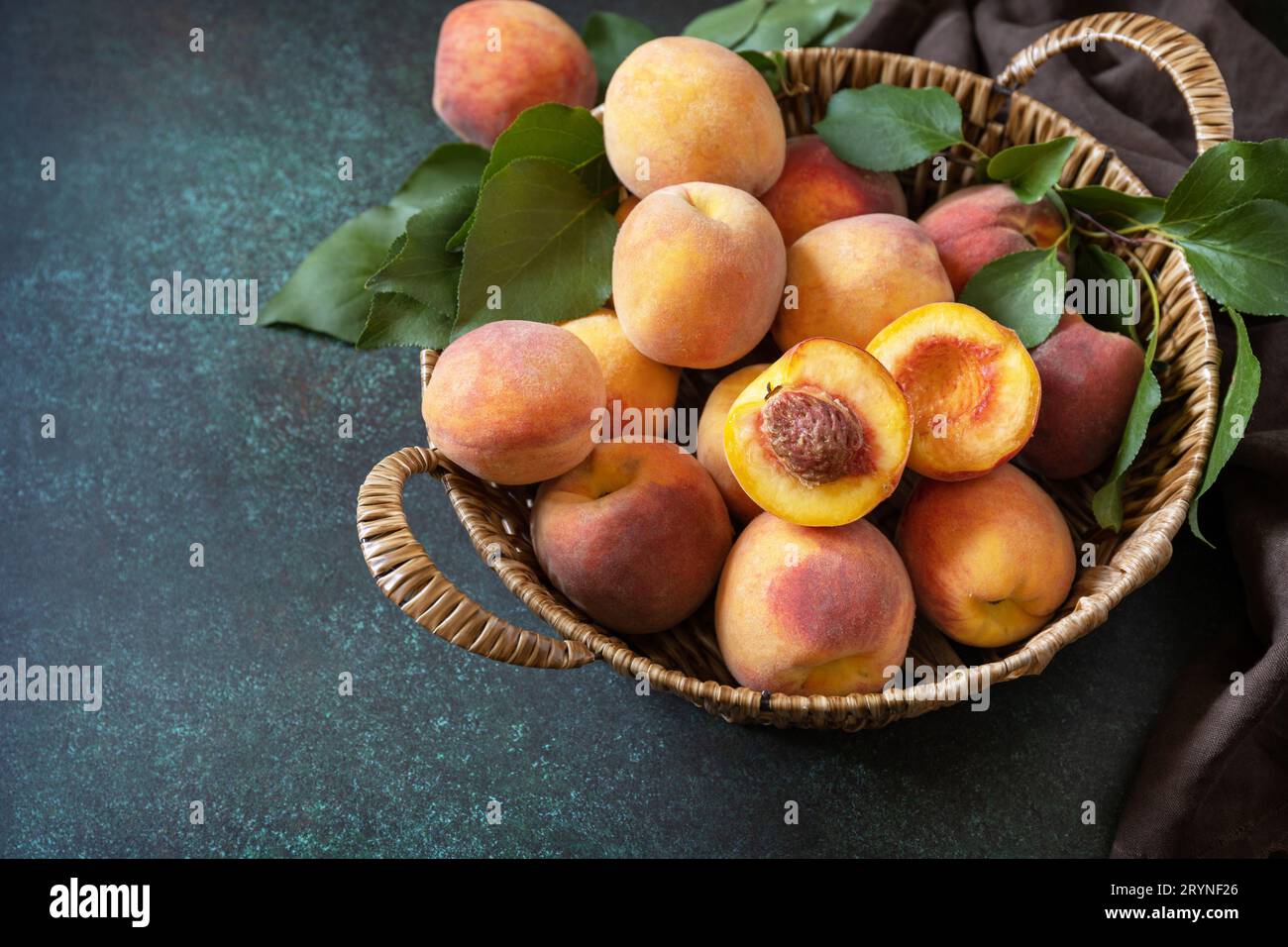 Sfondo del raccolto. Frutta biologica. Mercato agricolo. Cestino di pesche mature su un tavolo di pietra. Copia spazio. Foto Stock