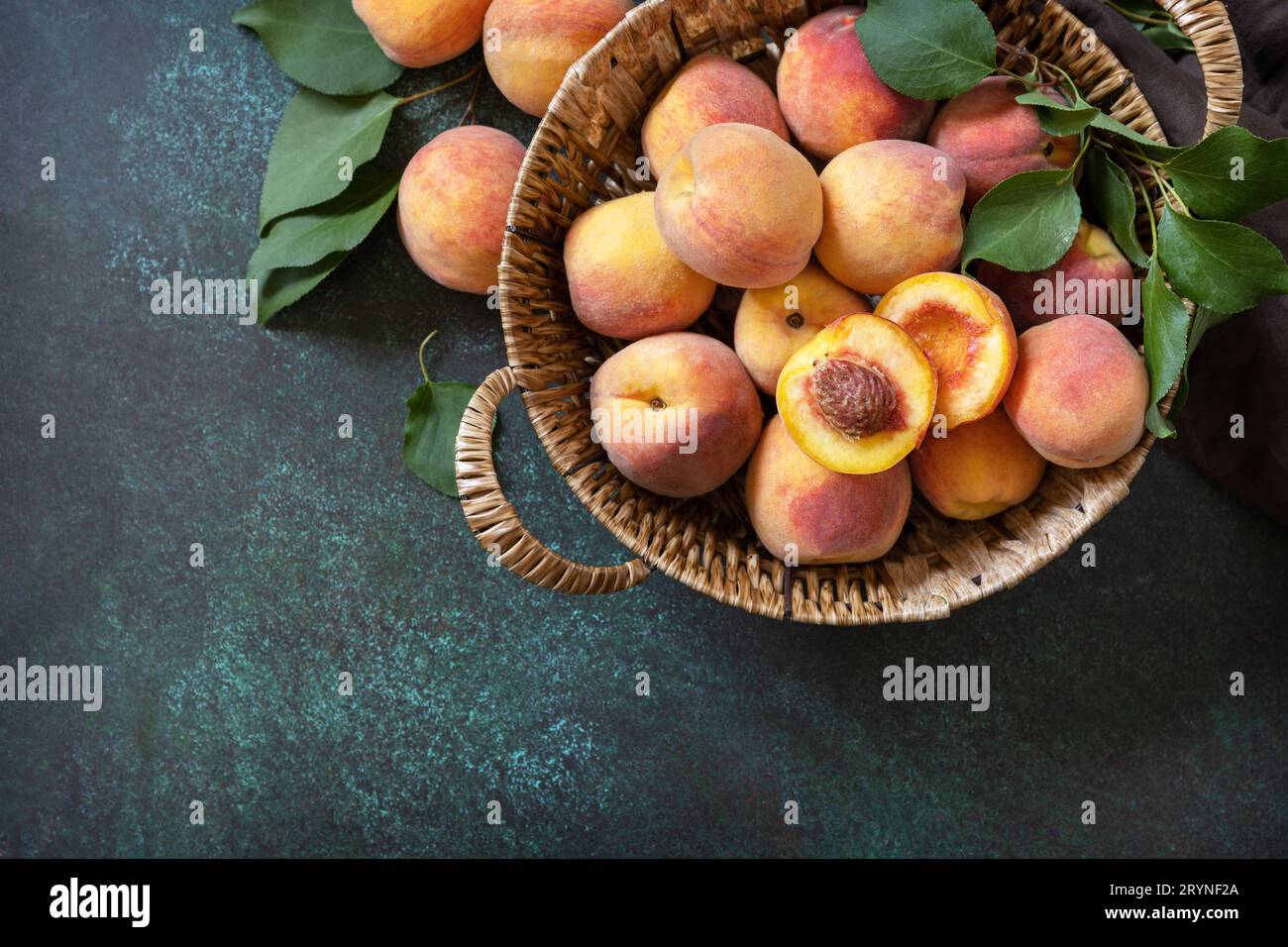 Sfondo del raccolto. Frutta biologica. Mercato agricolo. Cestino di pesche mature su un tavolo di pietra. Vista dall'alto. Copia spazio. Foto Stock