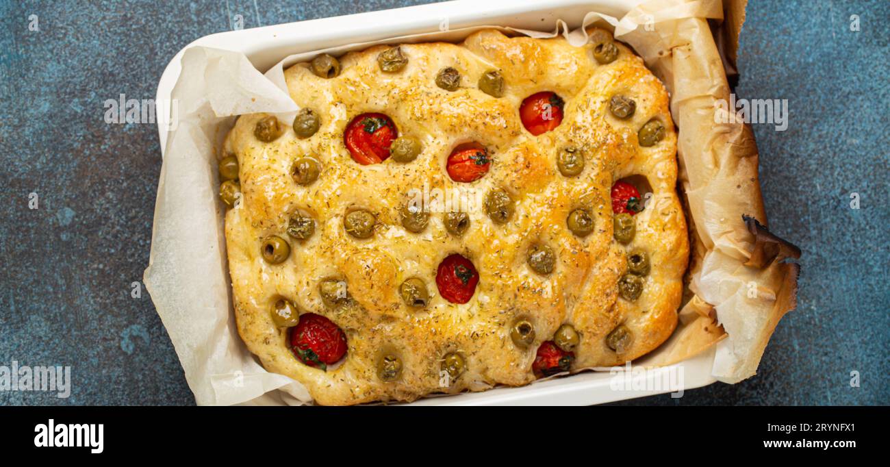 Sopra la tradizionale focaccia di pane piatto italiana fatta in casa con olive verdi, olio d'oliva, pomodori ciliegini e rosmarino nel Bakin Foto Stock