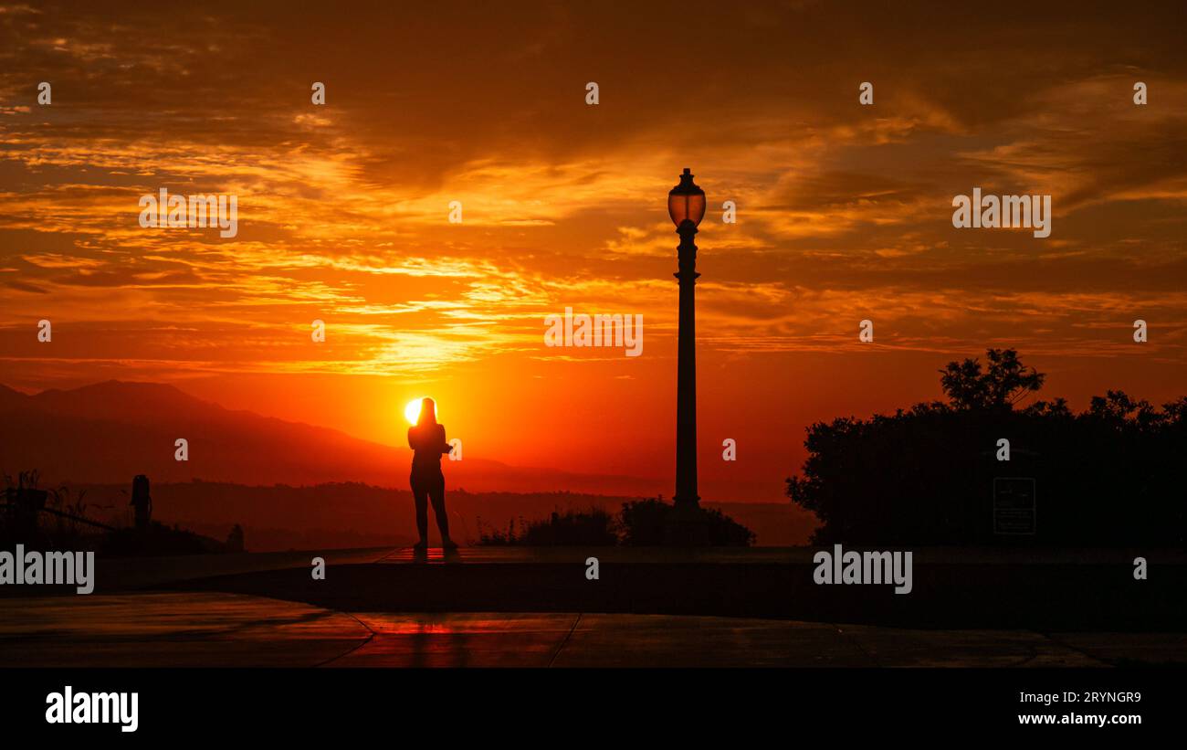 Donna che ammira l'alba sulla cima di una montagna dopo l'allenamento Foto Stock