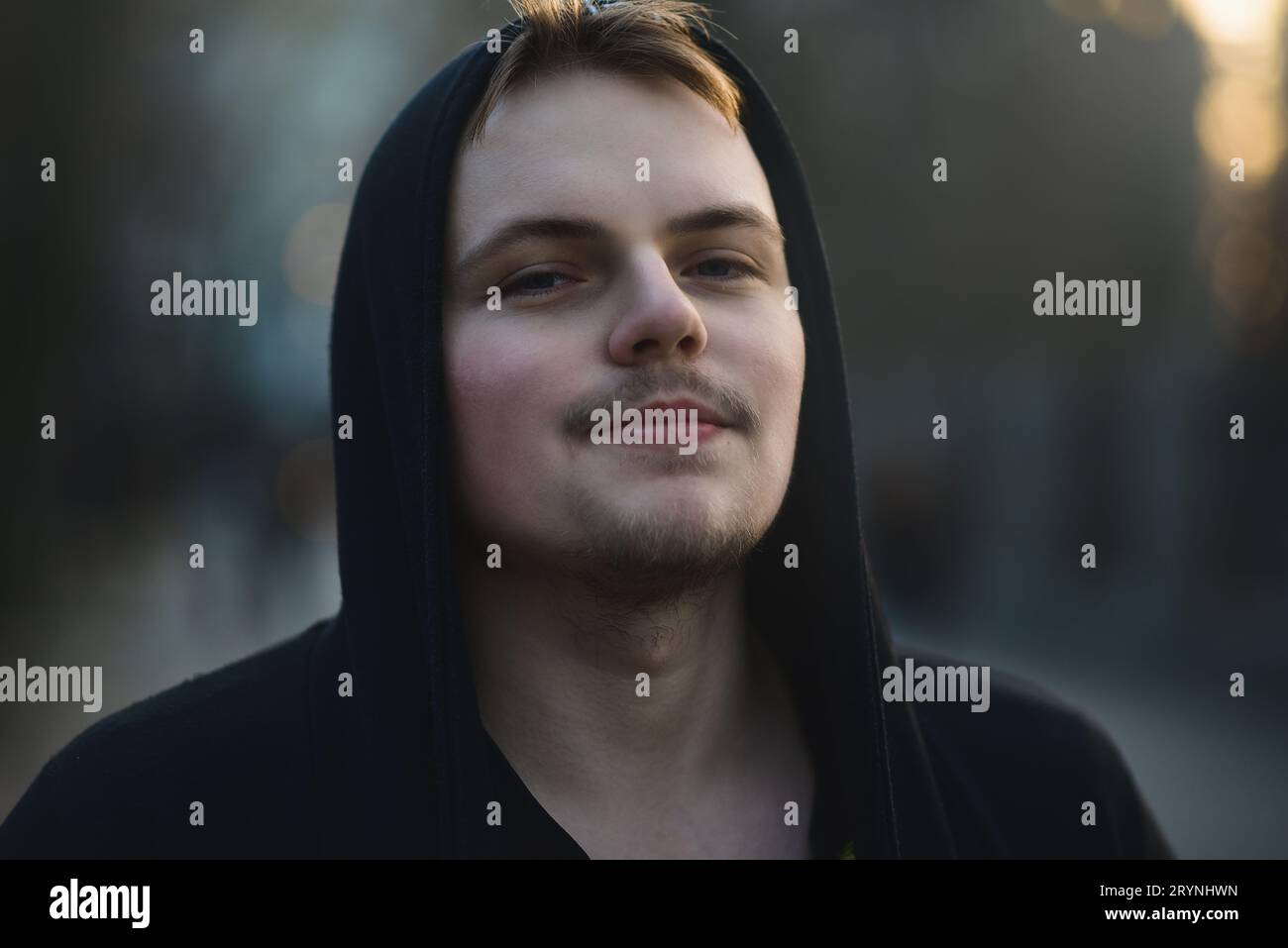 Ritratto di un bellissimo giovane uomo che indossa il cappuccio, adolescente del parco naturale che è premuroso e contemplativo, stile di vita ricreativo. Foto Stock