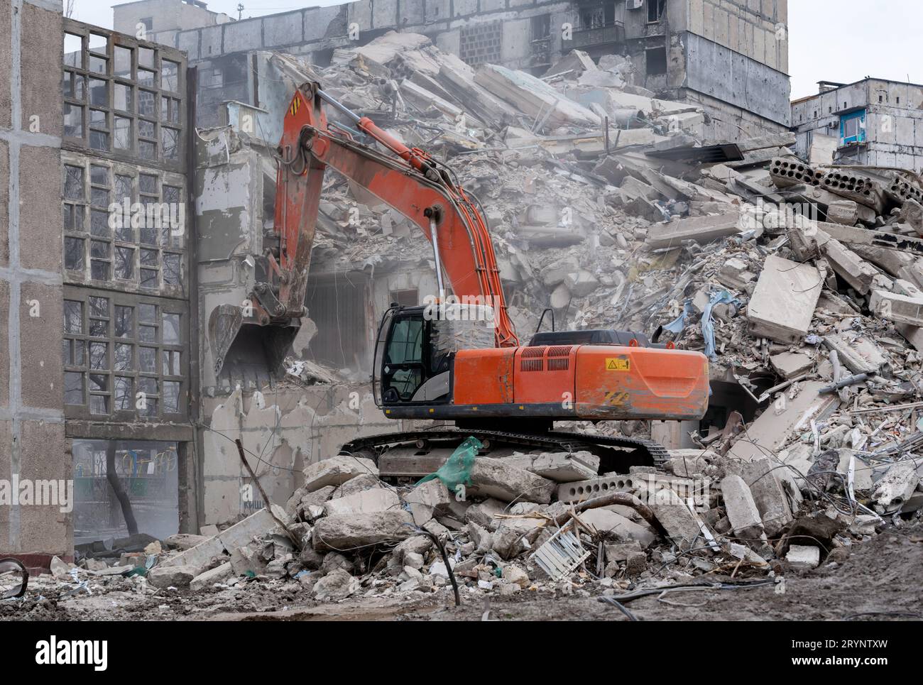 Le attrezzature da costruzione distruggono le case colpite dalla guerra in Ucraina Foto Stock