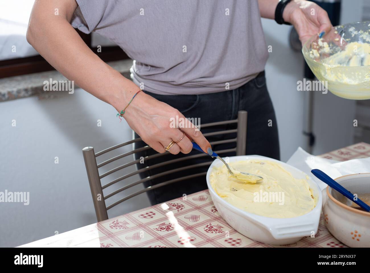 le mani della donna preparano il tiramisù. Tipico dessert italiano Foto Stock