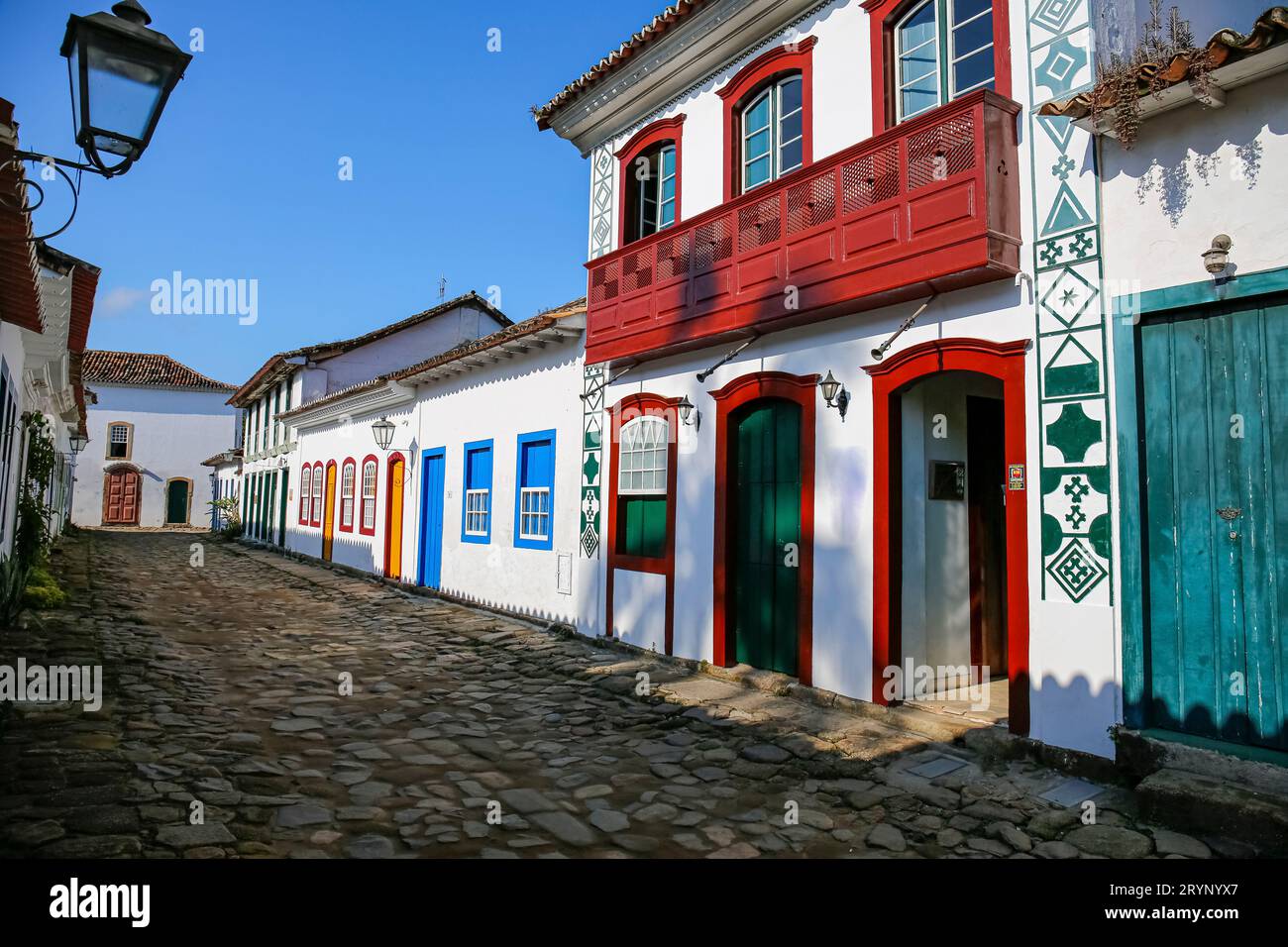 Tipica strada acciottolata con edifici coloniali decorativi e colorati alla luce del tardo pomeriggio nella storica città di Paraty, Braz Foto Stock