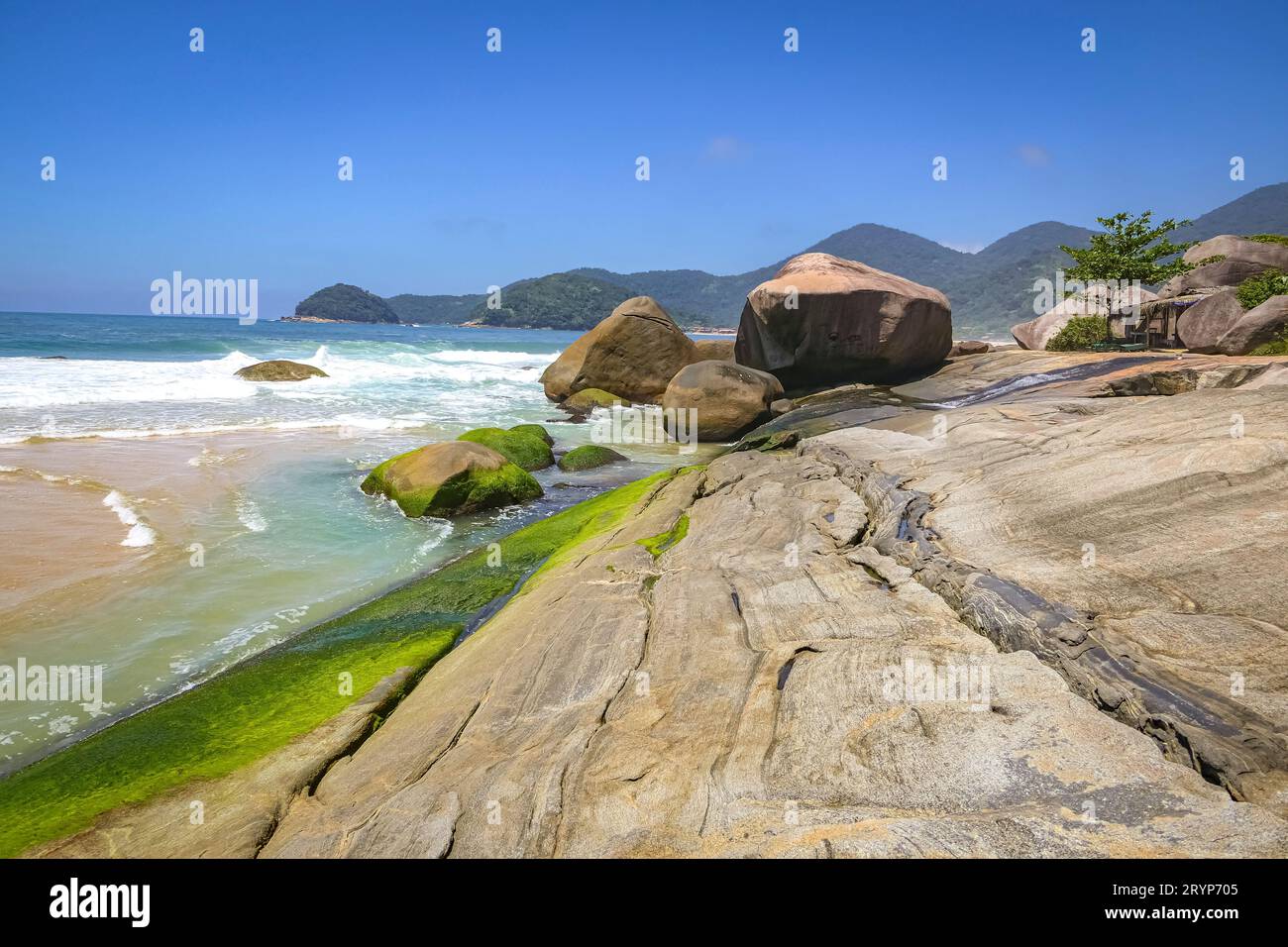 Ammira la splendida costa con lastre di roccia e montagne sullo sfondo, Picinguaba, Brasile Foto Stock