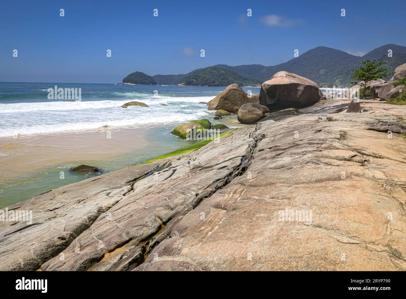 Ammira la splendida costa con lastre di roccia e montagne sullo sfondo, Picinguaba, Brasile Foto Stock
