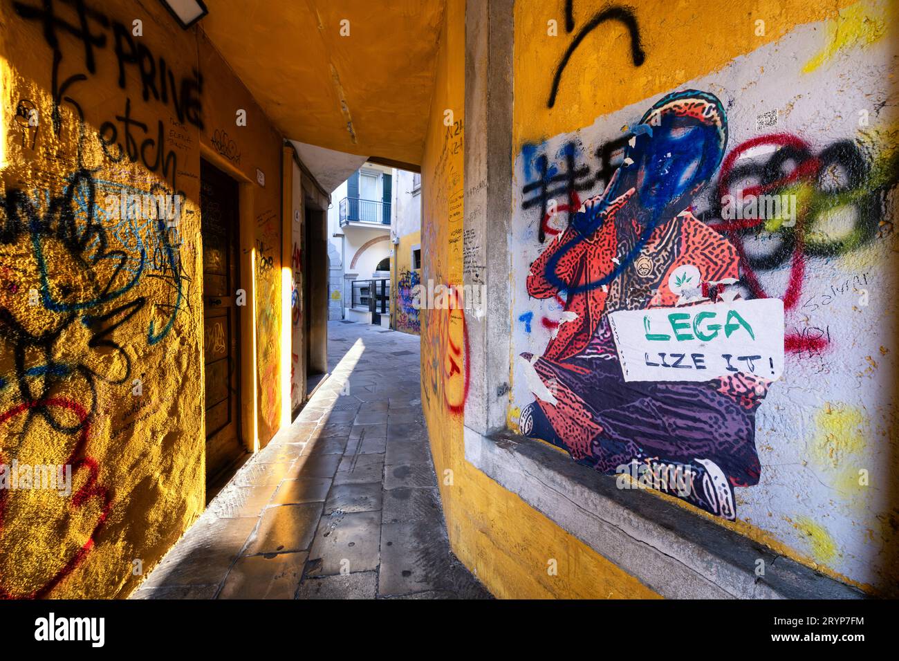 Graffiti su un muro di uno stretto vicolo italiano. Un uomo seduto mostra una lavagna con la frase "legalizzare". La Lega scritta in verde si riferisce al partito. Foto Stock