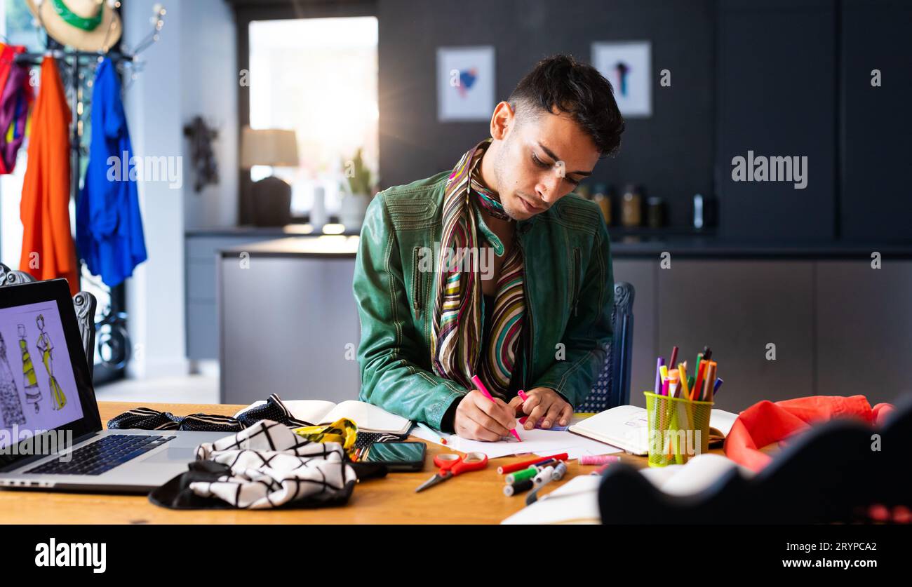 Designer di moda transgender biraciale seduto alla scrivania, utilizzando un laptop e schizzi di disegno. Genere, moda, design, comunicazione e stile di vita, unalte Foto Stock
