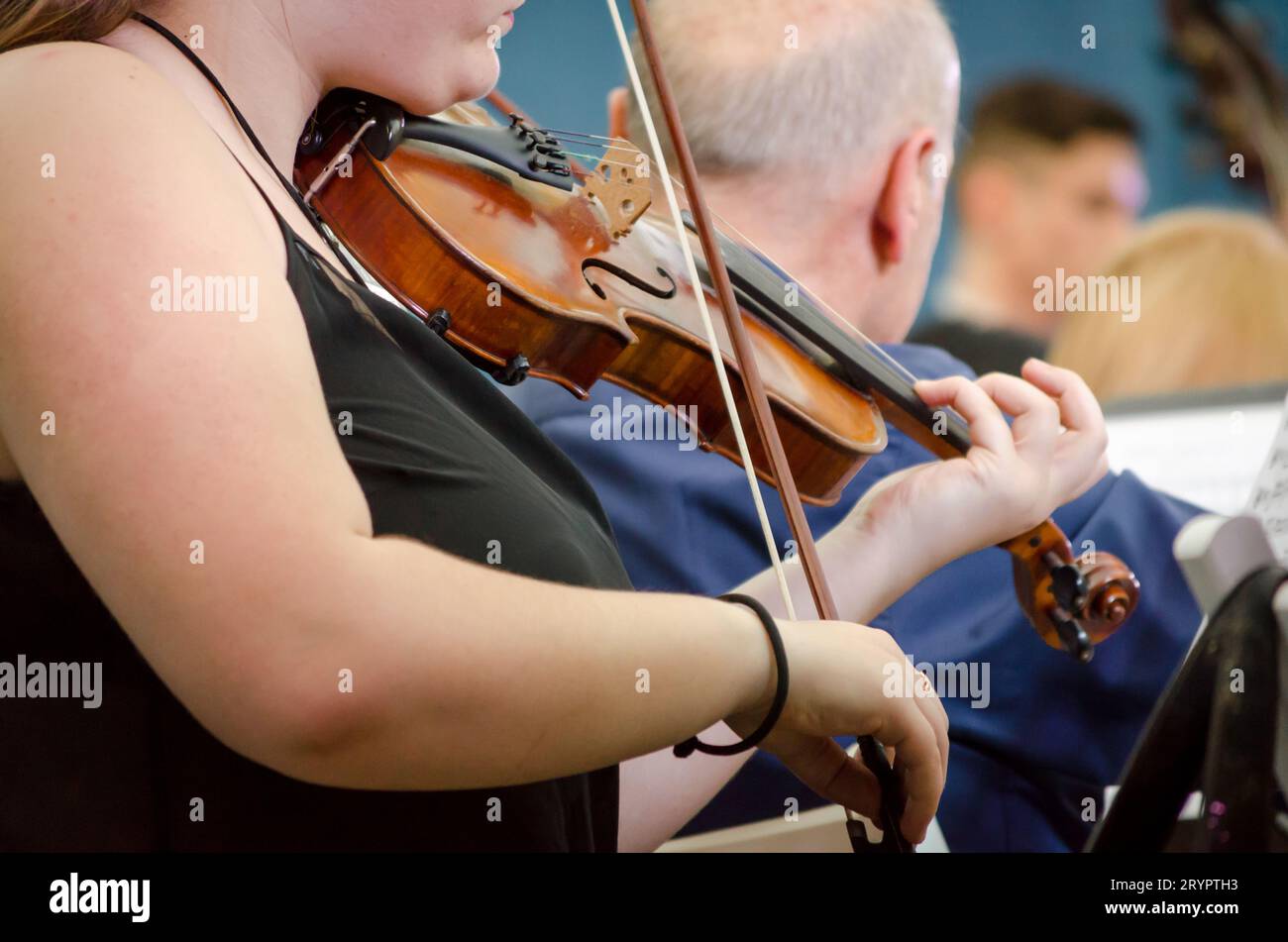 Musicista femminile che suona un violino con un'orchestra sinfonica Foto Stock