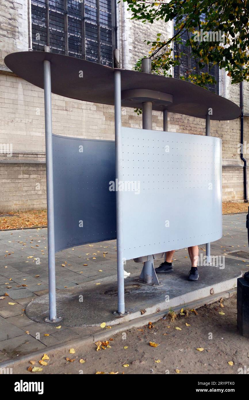 Uomo che usa orinatoio pubblico gratuito nel centro di Bruxelles, in Belgio. E' illegale urinare in uno spazio pubblico di Bruxelles. Foto Stock