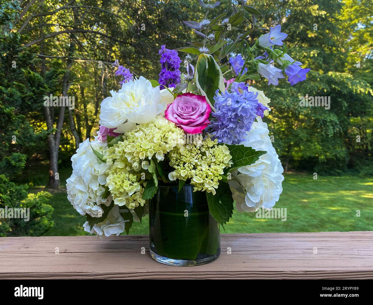 Bouquet di fiori colorati in vaso di vetro nel giardino primaverile. Foto Stock