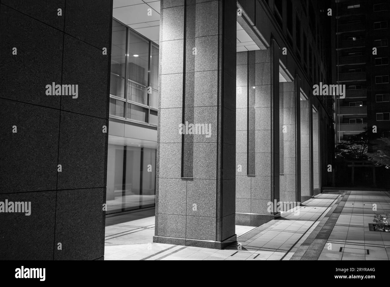 Una foto media di una strada cittadina caratterizzata da grandi colonne di pietra che si trovano all'ingresso di una porta che emette una luce brillante Foto Stock