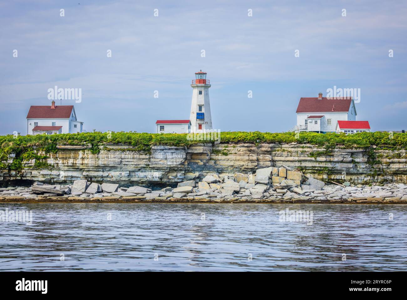 Un pittoresco faro sorge sulla cima di una scogliera rocciosa, che si affaccia sulle splendide acque blu dell'oceano Foto Stock
