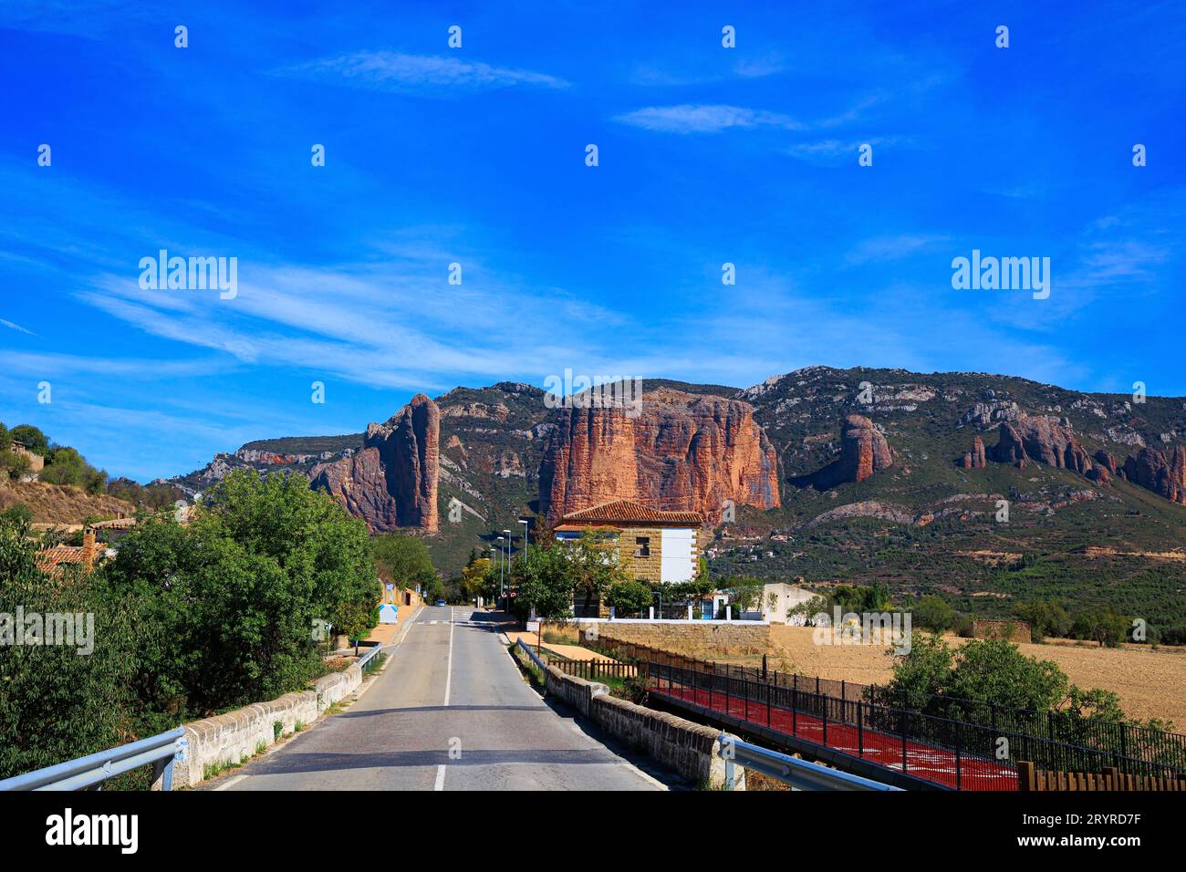 I pittoreschi Mallets di Riglos. L'autostrada asfaltata passa attraverso le rocce. Hoya de Huesca, Aragon. Parte delle colline pedemontane dei Pirenei. Caldo sole Foto Stock