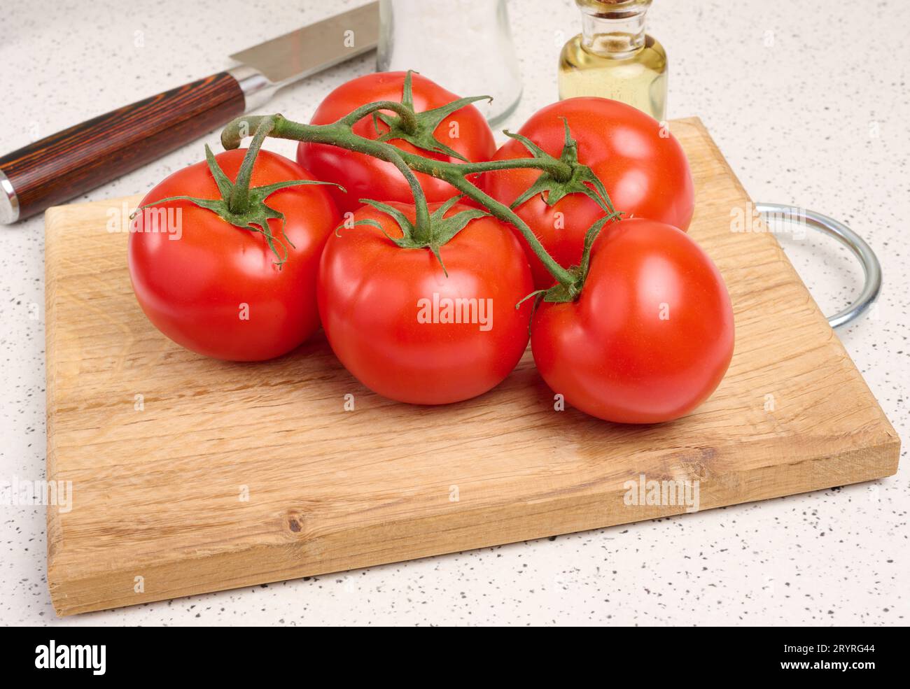 Pomodori rossi maturi su un ramo verde su una tavola bianca, verdura sana Foto Stock