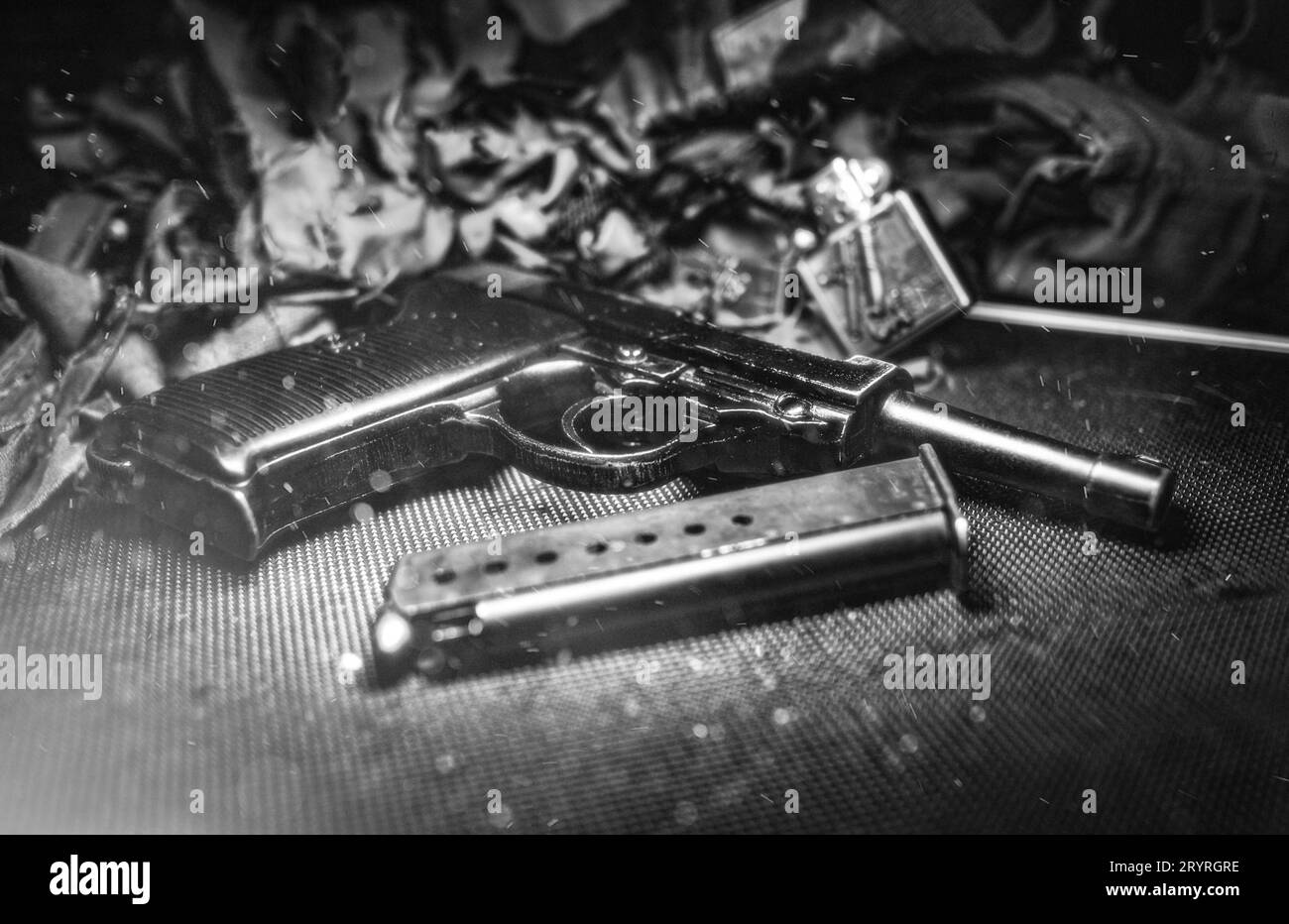 Una scala di grigi di una pistola con carte schiacciate sullo sfondo Foto Stock