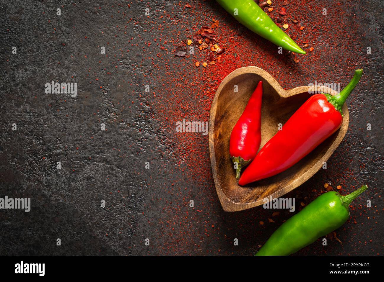 Spice Food sfondo scuro. Peperoncino rosso e verde in una ciotola di legno Foto Stock