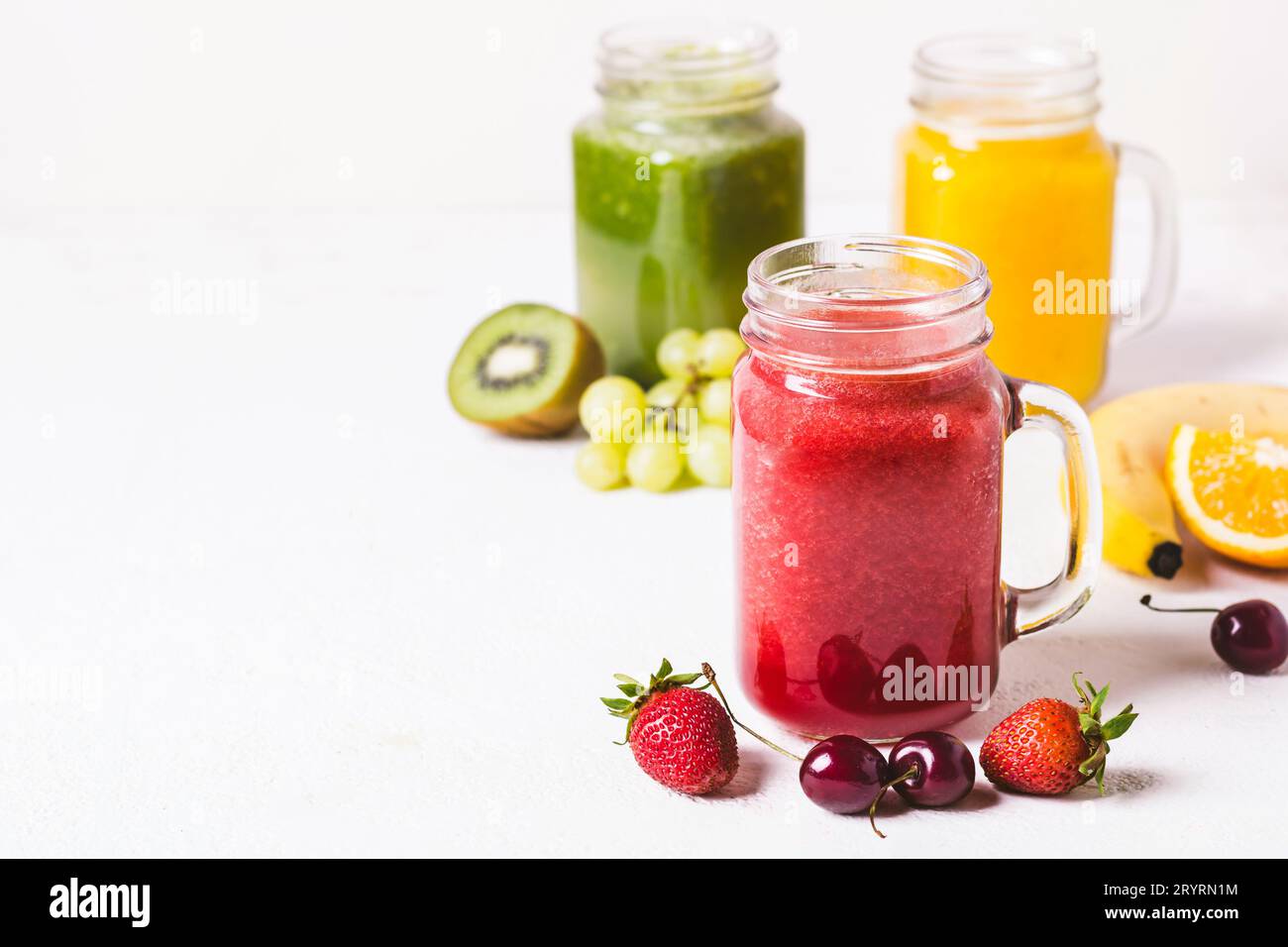 Frullato rosso, giallo e verde in un vaso di vetro e ingredienti Foto Stock