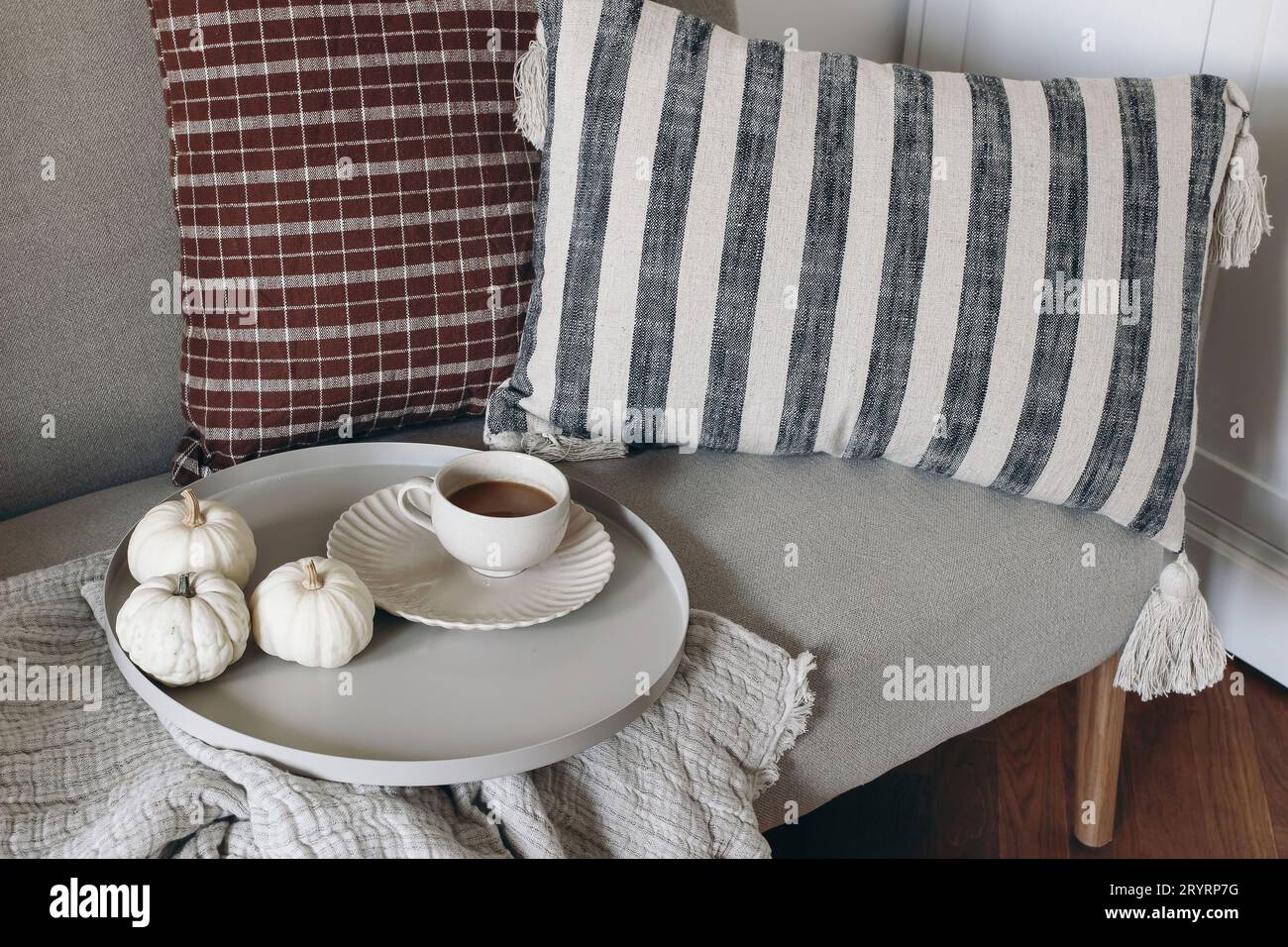 Dettagli decorativi STILL Life a casa. Interno del soggiorno. Tazza di caffè, vassoio rotondo Piccole zucche bianche. Colazione sul divano Foto Stock