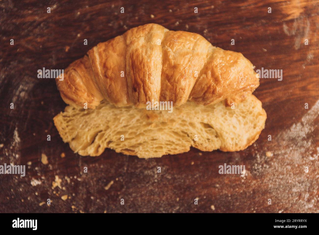 Vista dall'alto di due metà di un croissant appena sfornato su un tavolo di legno Foto Stock