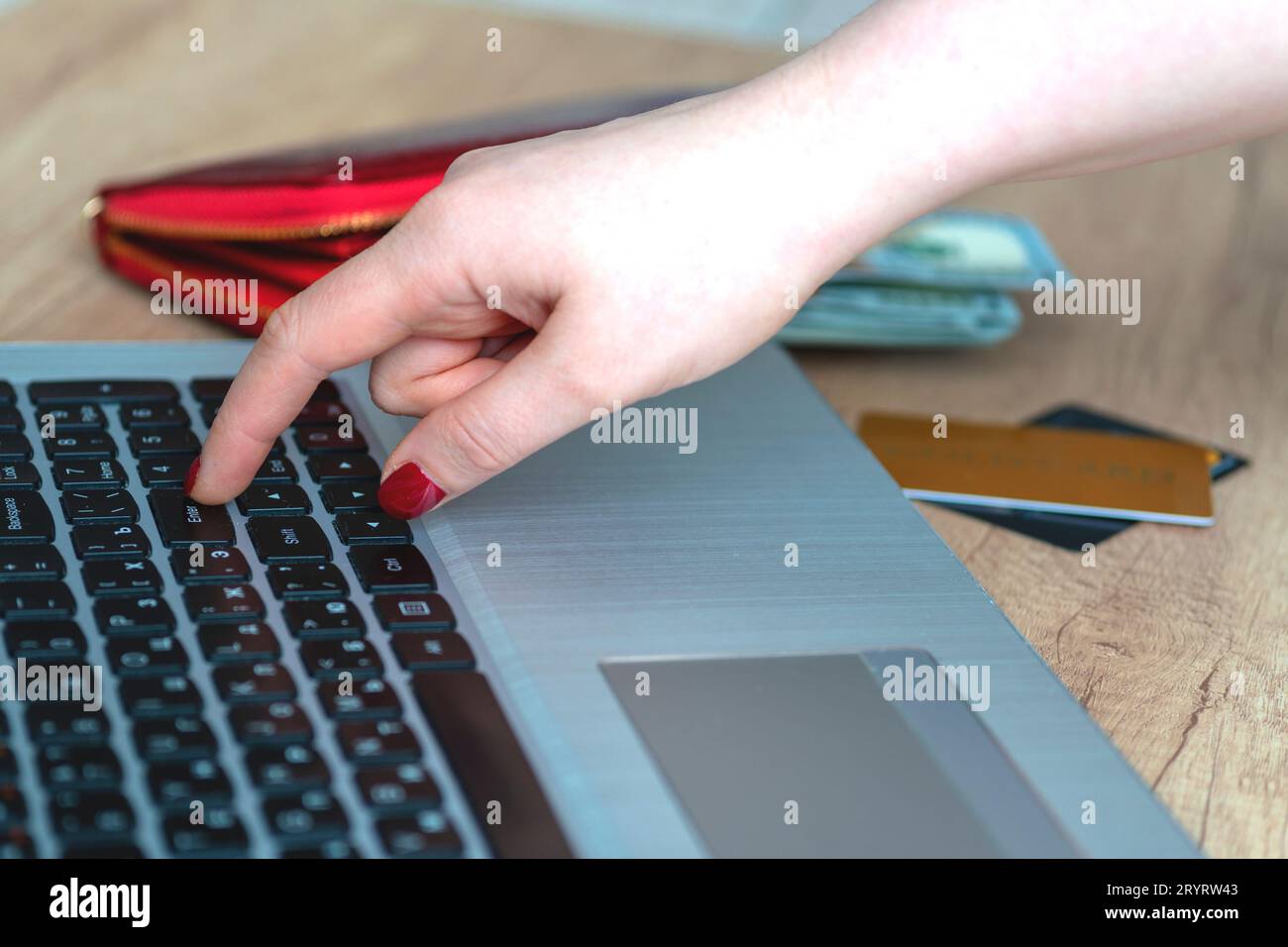Premere manualmente il tasto invio sullo sfondo del laptop. Mano, portafoglio, soldi, portatile, carta d'oro, carte. Concept Scegli e acquista prodotti online. Shopper. concetto Foto Stock