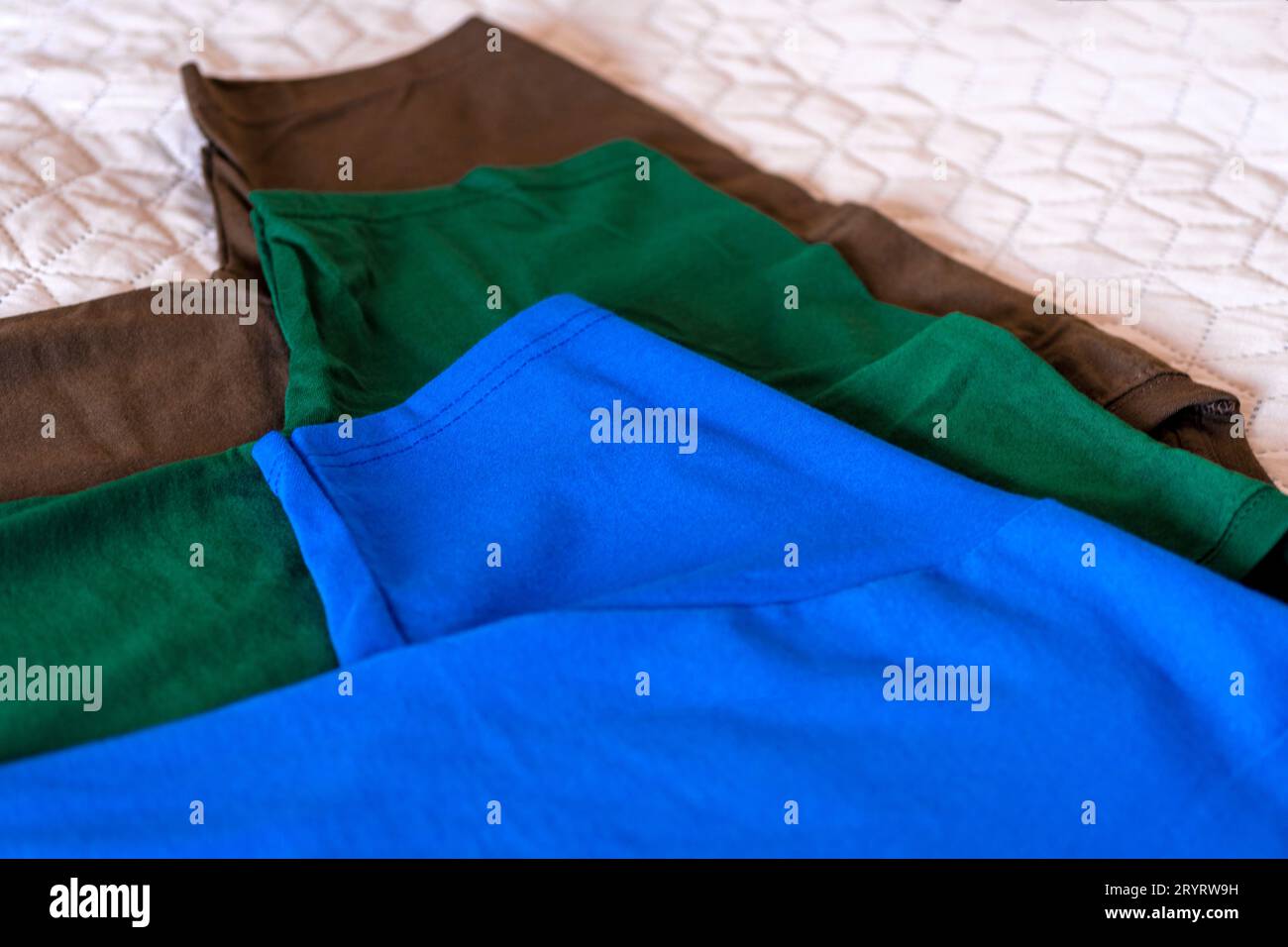 T-shirt ripiegate in diversi colori. Primo piano di diverse t-shirt colorate.T-shirt maniche primo piano. Nuovo concetto di abbigliamento sportivo. Sportswear nel negozio Foto Stock
