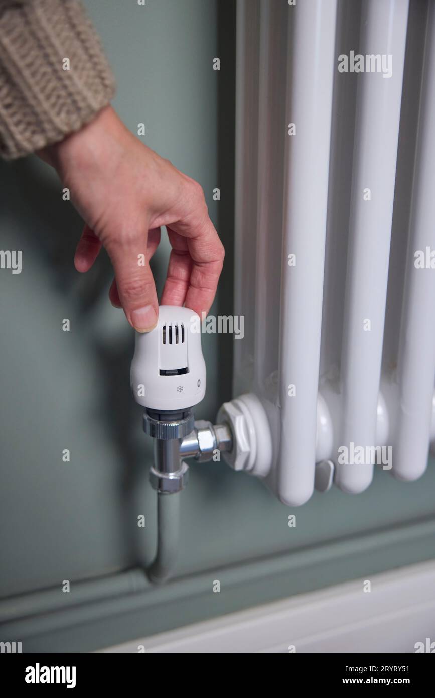 Primo piano della rotazione manuale del termostato sul radiatore a casa per risparmiare energia e denaro Foto Stock