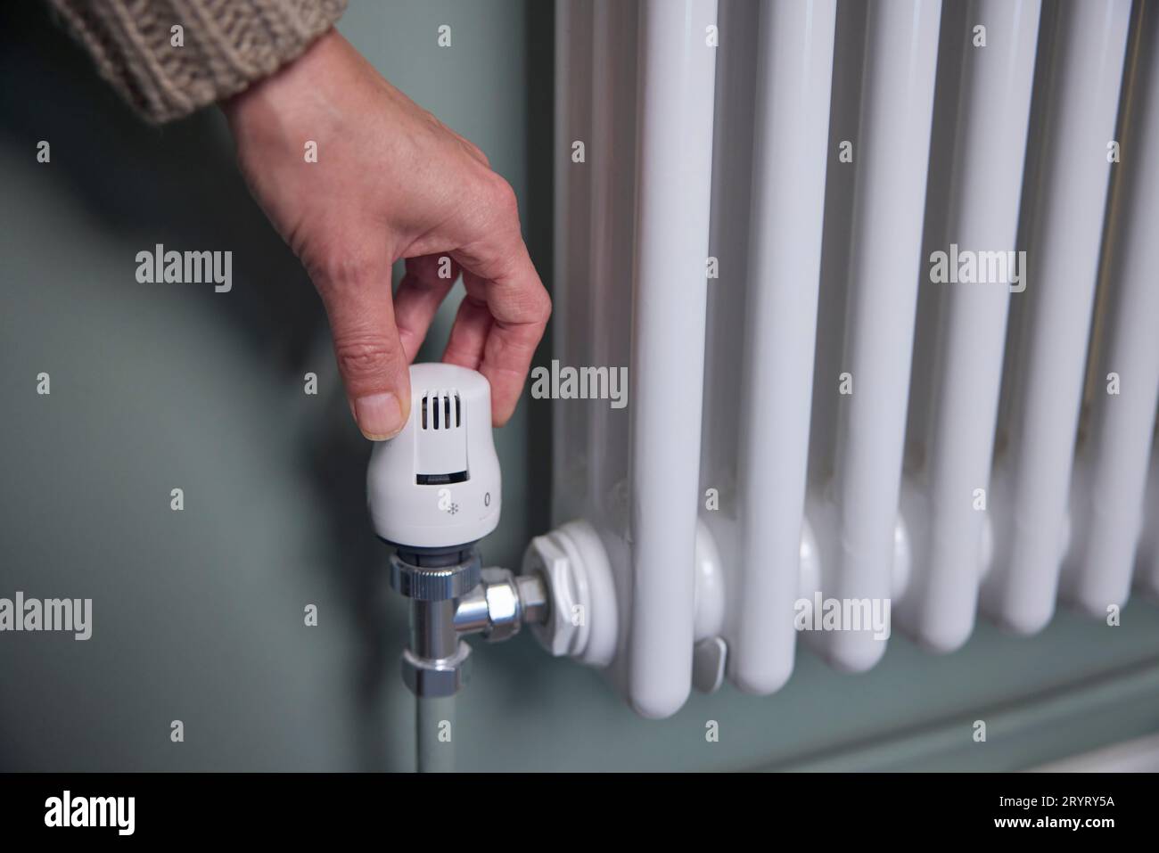 Primo piano della rotazione manuale del termostato sul radiatore a casa per risparmiare energia e denaro Foto Stock