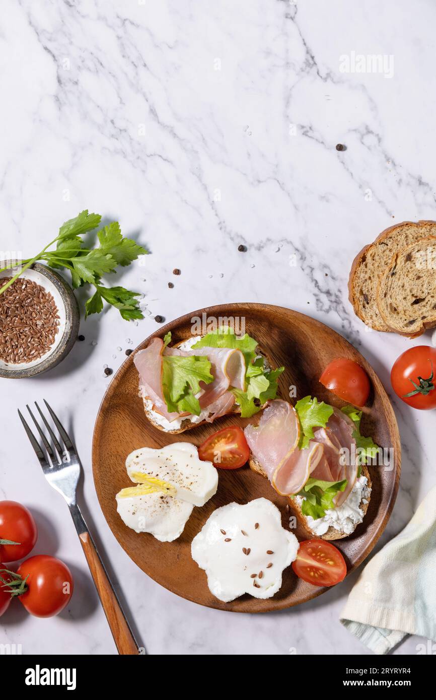 Colazione di Pasqua o brunch. Deliziosa colazione o spuntino: Uova in camicia e formaggio spalmabile, pane di segale integrale, prosciutto, Foto Stock