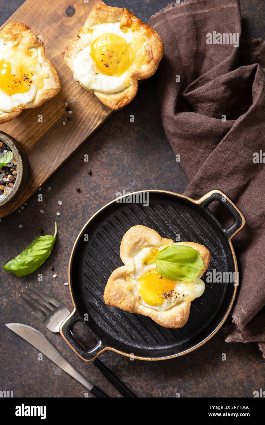 Uova strapazzate in pasta sfoglia con formaggio e pancetta su un piatto di pietra. Idea di colazione, spuntini. Vista dall'alto. Foto Stock