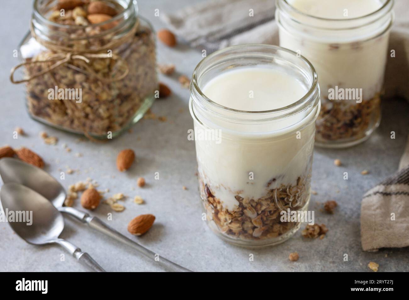 Colazione sana, yogurt parfait. Yogurt con granola di mandorle fatta in casa su sfondo grigio di cemento. Foto Stock