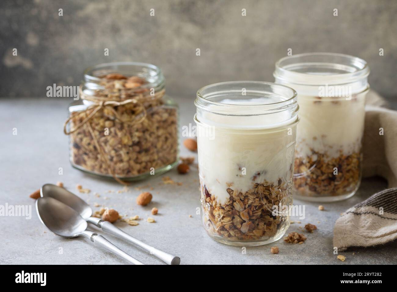 Colazione sana, yogurt parfait. Yogurt con granola di mandorle fatta in casa su sfondo grigio di cemento. Spazio di copia. Foto Stock