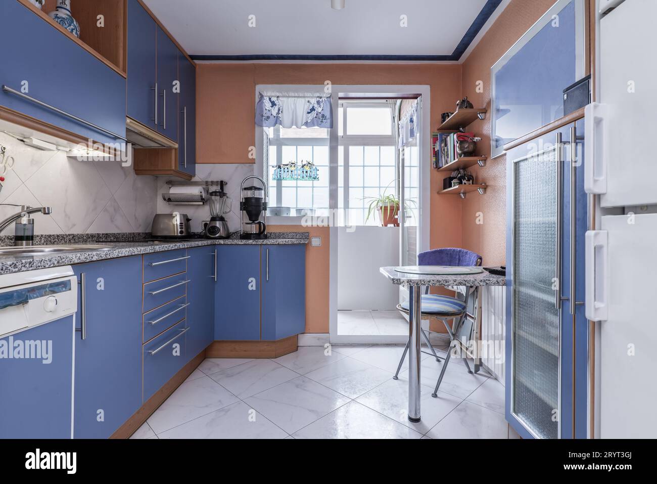 Cucina con parete piena di armadietti blu con dettagli in legno di ciliegio Foto Stock