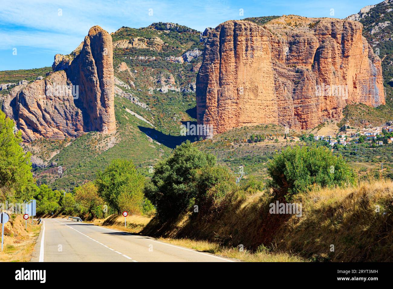 L'autostrada asfaltata passa attraverso le rocce. Hoya de Huesca, Aragon. Parte delle colline pedemontane dei Pirenei. I Mallets di Riglos. Pomeriggio di sole. Roman Foto Stock