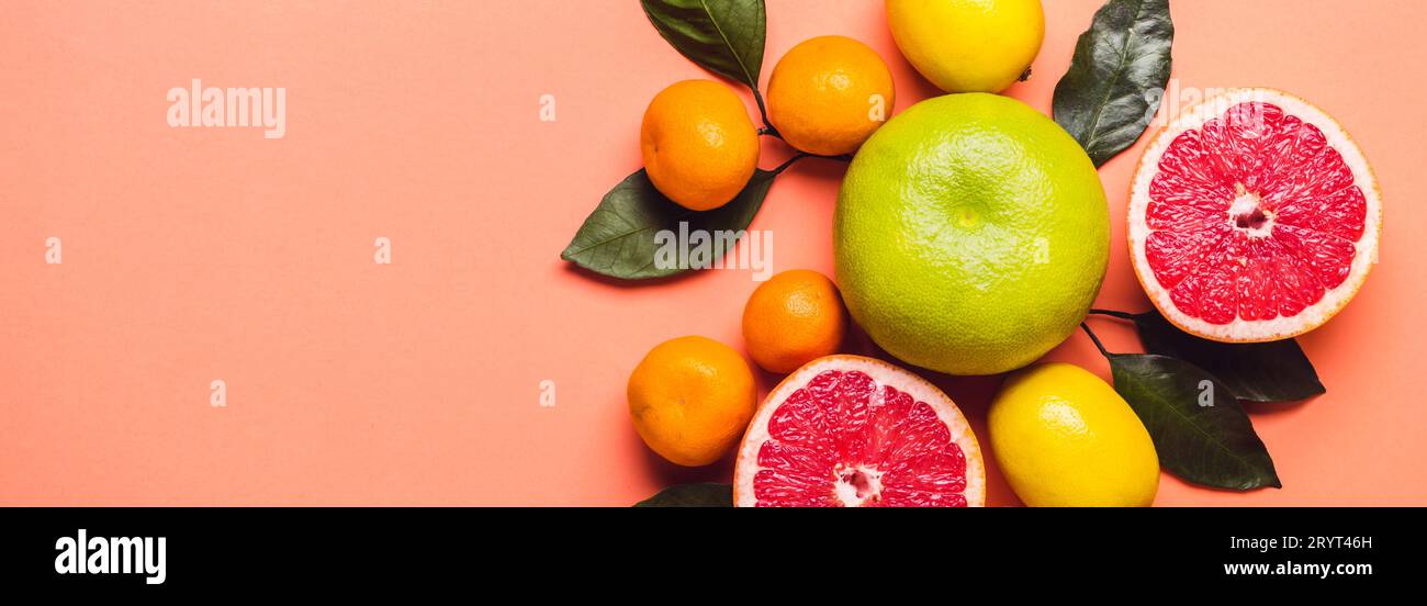 Pompelmo circondato da limoni e mandaroini. Sfondo corallino vivo. Trend colore 2019 Foto Stock