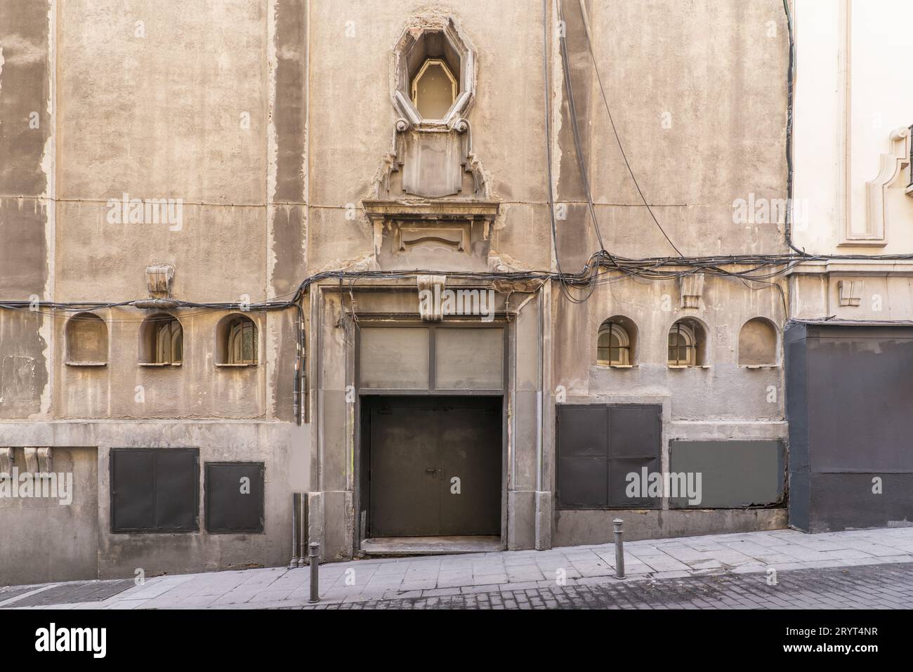 Facciata di un edificio molto vecchio con conci di granito, finestre con vecchie ringhiere in ferro battuto e pavimenti in pietra rinnovati Foto Stock