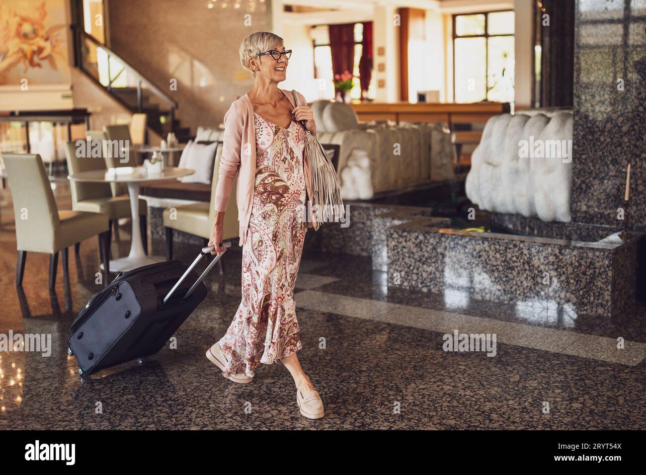 Una donna matura viene in hotel alla reception. Foto Stock