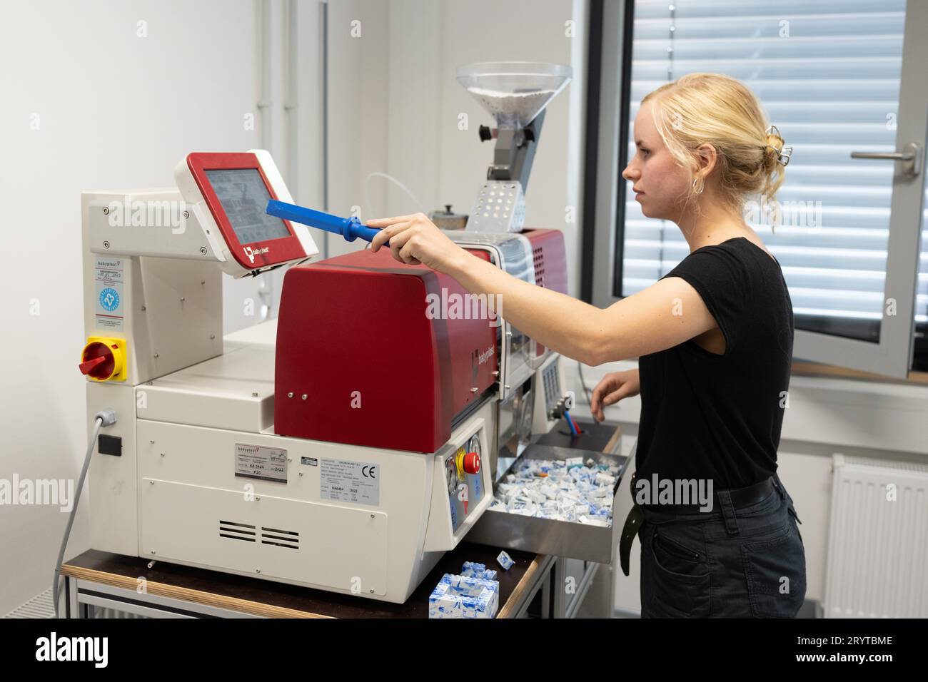 Dresda, Germania. 2 ottobre 2023. Dorothee Wendler, ingegnere delle materie plastiche, gestisce una macchina per lo stampaggio a iniezione presso la HolyPoly, una società di riciclaggio con sede a Dresda. L'azienda sviluppa programmi di riciclaggio personalizzati per recuperare la plastica pura dai rifiuti di plastica mista. Credito: Sebastian Kahnert/dpa/Alamy Live News Foto Stock