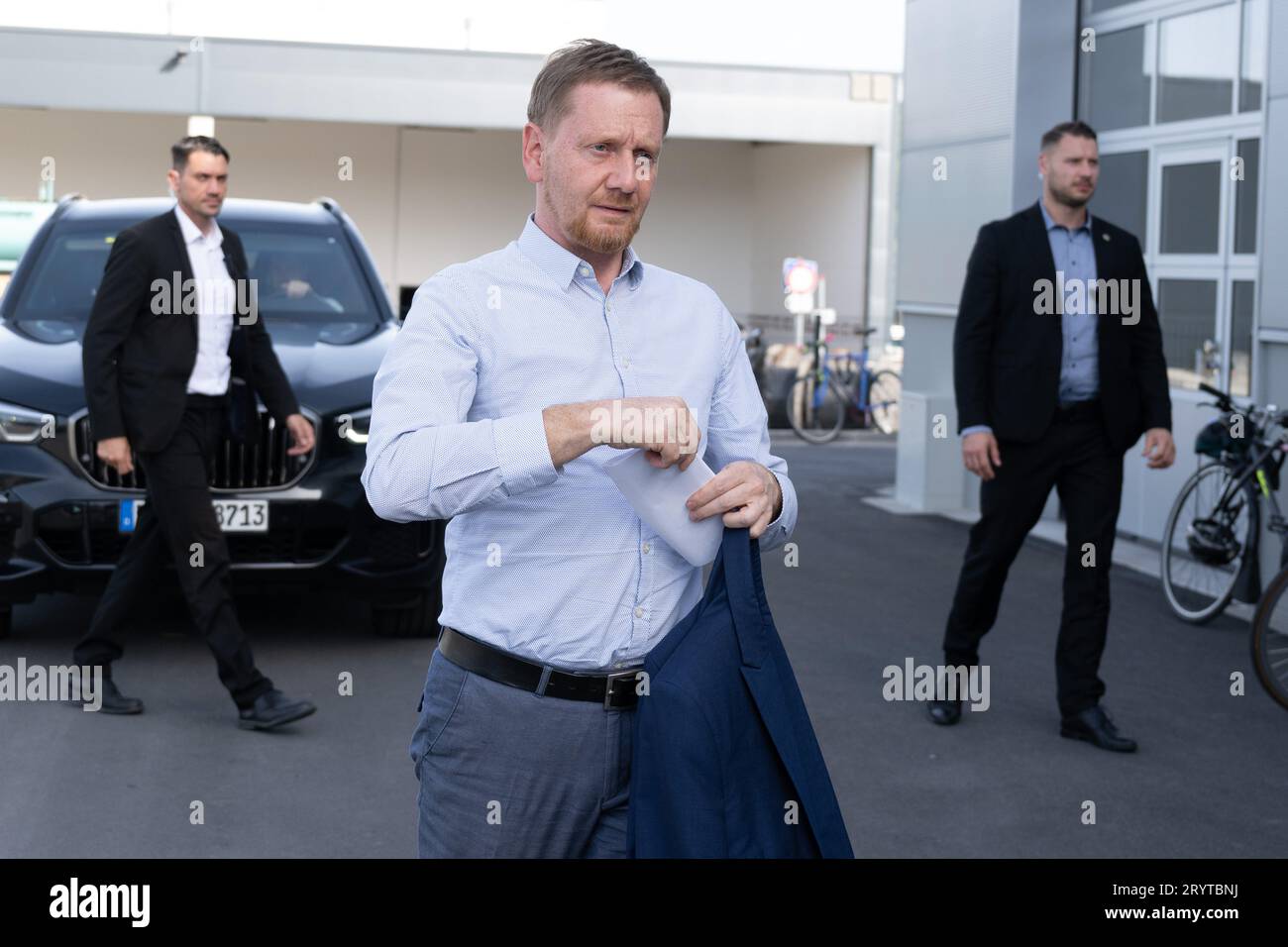 Dresda, Germania. 2 ottobre 2023. Michael Kretschmer (CDU), ministro presidente della Sassonia, si trova di fronte alla sua auto ufficiale durante la sua visita alla HolyPoly, una Start-up di riciclaggio con sede a Dresda. L'azienda sviluppa programmi di riciclaggio personalizzati per il recupero di materie plastiche monovarietà da rifiuti plastici misti. Credito: Sebastian Kahnert/dpa/Alamy Live News Foto Stock