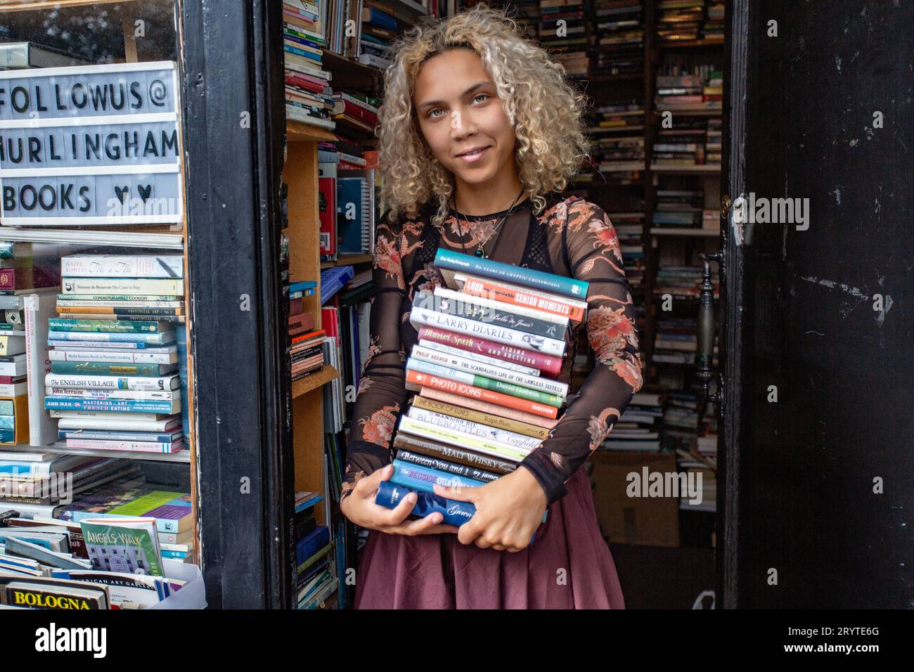 GREAT BRITAN / Londra / Hurlingham Books / attraente donna che tiene una pila di libri. Foto Stock