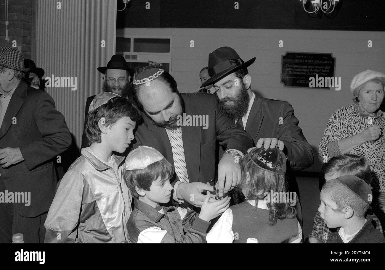 La prima cerimonia di taglio dei capelli di Upshernish per un bambino ebreo di tre anni. E' una tradizione ebraica consacrata nel tempo permettere che i capelli di un ragazzo diventino intatti per i primi anni di vita.1 al suo terzo compleanno ebraico, amici e membri della comunità sono invitati a una cerimonia festiva di taglio dei capelli: L'upshernish (“shearing”) in yiddish, o chalakah in ebraico. Qui Yehudah Lieb figlio di Rabbi Herchel Rader della congregazione Solihull è il soggetto felice. I membri della congregazione prendono il loro turno per tagliare e tagliare un piccolo pezzo di capelli del giovane. Foto Stock
