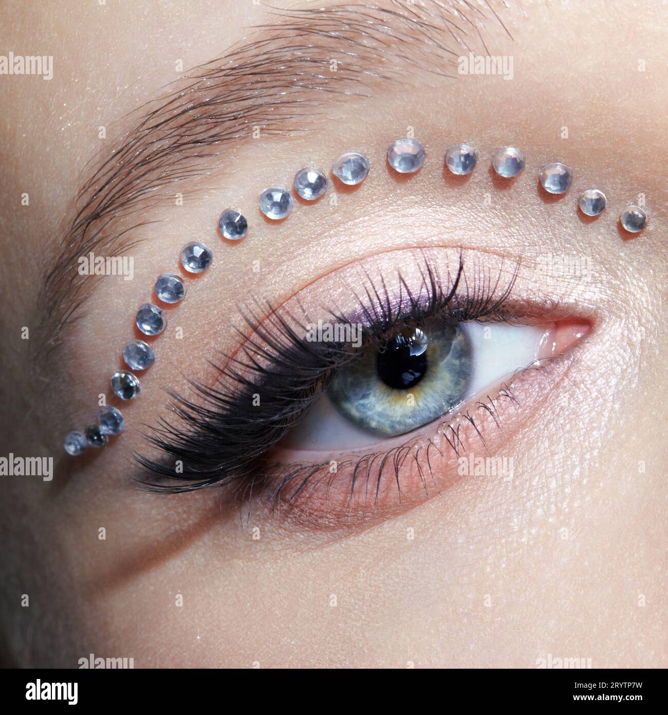 Primo piano macro shot di occhio umano femminile con trucco insolito. Donna con frecce di rhinestones sulla palpebra. Foto Stock