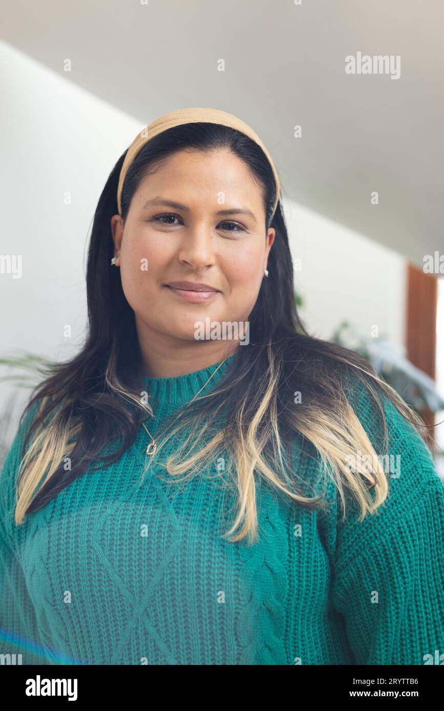 Ritratto di felice donna birazziale con capelli lunghi e lisci in una casa soleggiata Foto Stock