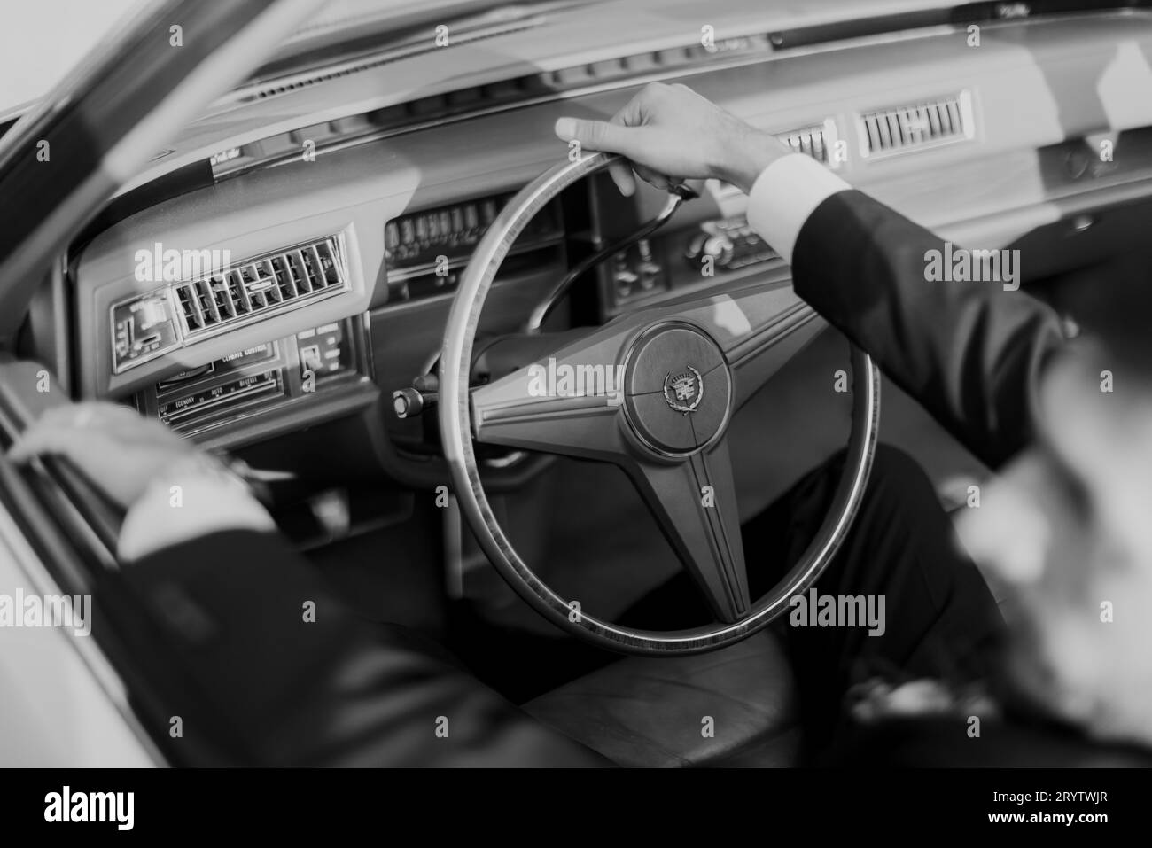 Una foto in scala di grigi di un uomo che guida un classico veicolo retrò Foto Stock