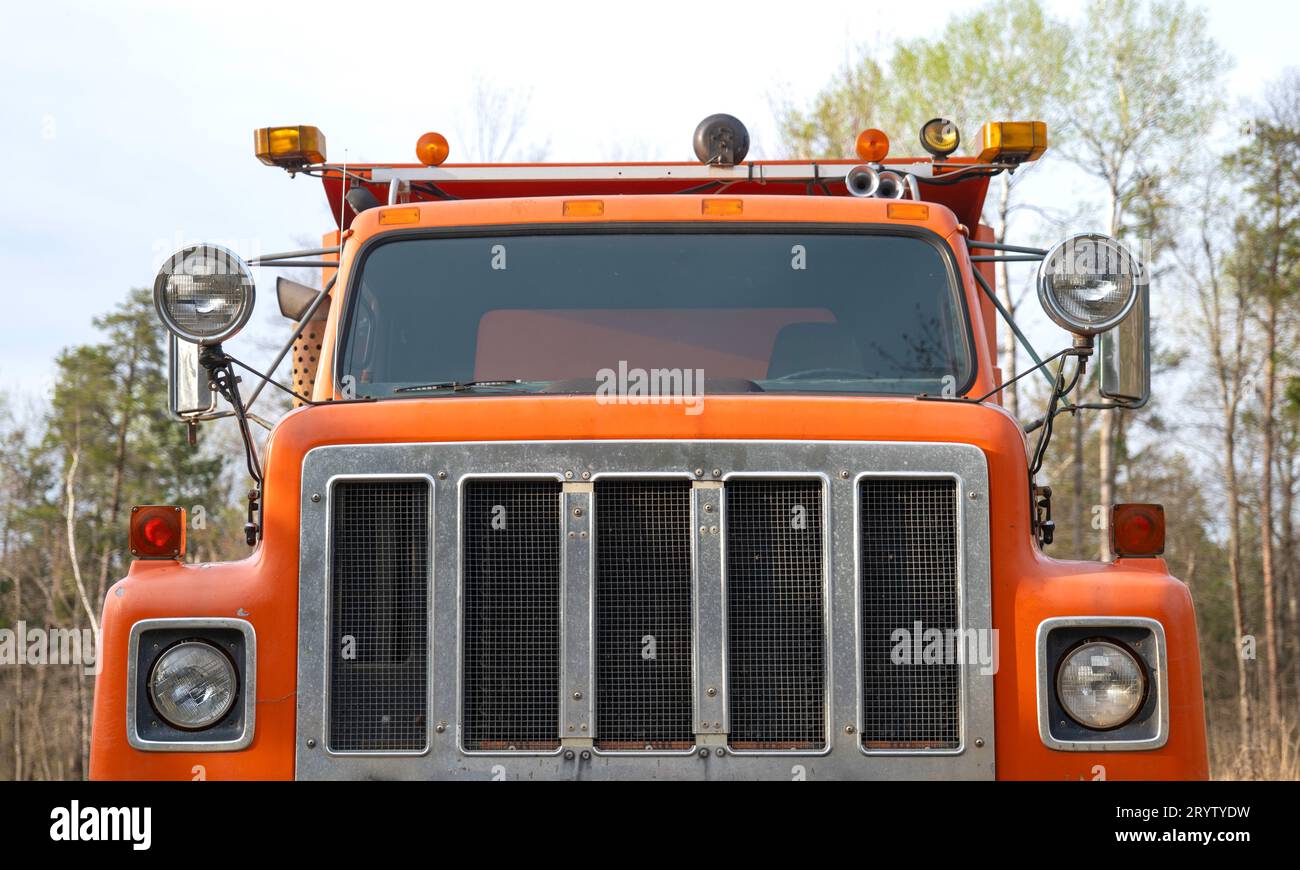 Vista ravvicinata della griglia anteriore di un vecchio camion con cassone ribaltabile arancione ben utilizzato. Foto Stock