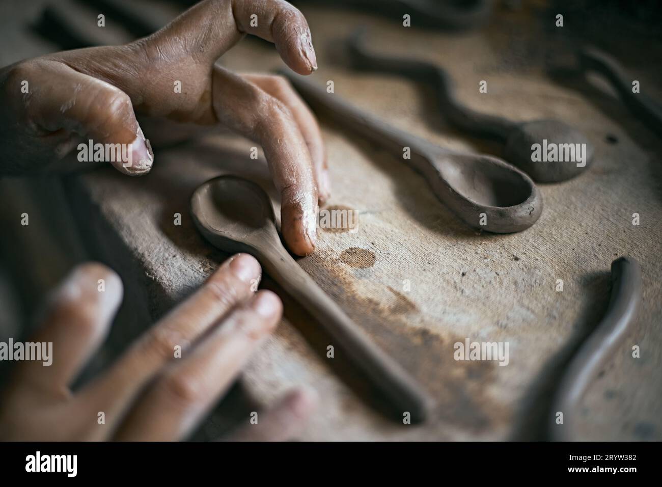Primo piano di mani che danno forma a un cucchiaio di argilla Foto Stock